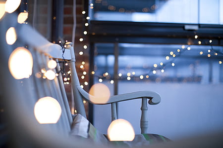 shallow focus photography of white wooden bench surrounded by light bokeh of string lights thumbnail
