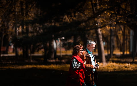 man and woman walking near tall tress during daytime thumbnail