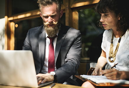 man wearing black suit holding laptop beside woman taking note thumbnail