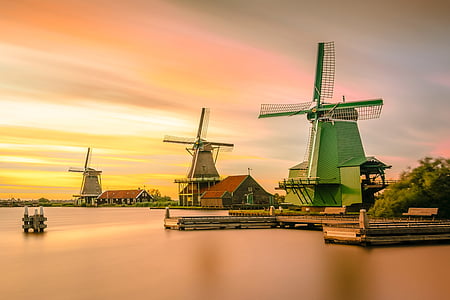 green windmill near body of water at sunset thumbnail