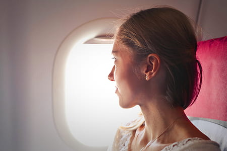 Selective Focus Photo of Woman Sitting on Chair Looking Outside Window on Plane thumbnail