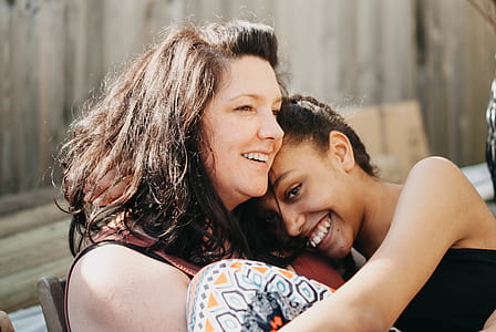 smiling woman hugging the woman wearing black top thumbnail