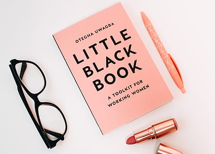 Little Black Book Surrounded With Pink Click Pen, Red Lipstick, and Black Wayfarer Eyeglasses thumbnail
