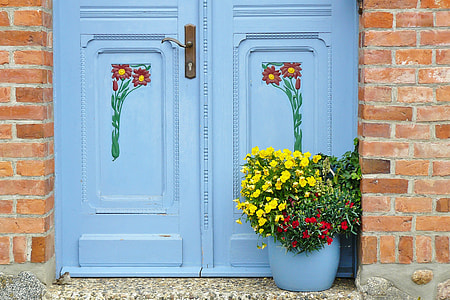 yellow and red flower arrangement beside blue wooden door thumbnail