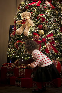 girl holding gifts under Christmas tree thumbnail