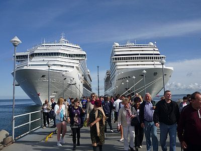 people walking on gray dock between two white cruise ships during daytime thumbnail