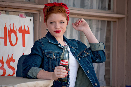 woman in blue denim jacket holding Coca-cola bottle thumbnail