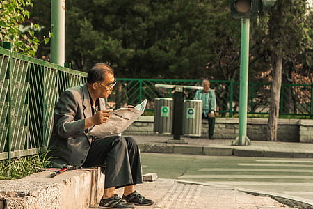 man reading newspaper near road thumbnail