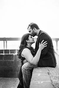 Man In Black Coat Sitting While Kissing Woman thumbnail