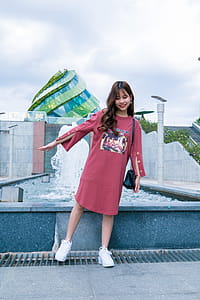 Woman Standing Beside Gray Concrete Outdoor Fountain Under Blue and White Cloudy Skies at Daytime thumbnail