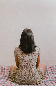 woman sitting on mattress while facing wall thumbnail