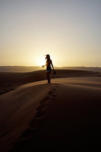 silhouette photo of woman standing on sand dune thumbnail