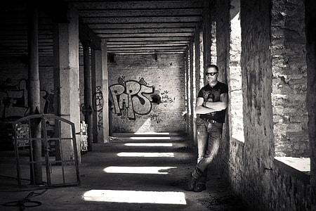grayscale photography of man leaning on wall inside building thumbnail