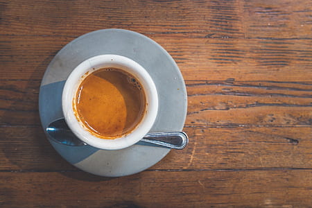 ceramic cup with coffee beside gray stainless steel spoon thumbnail