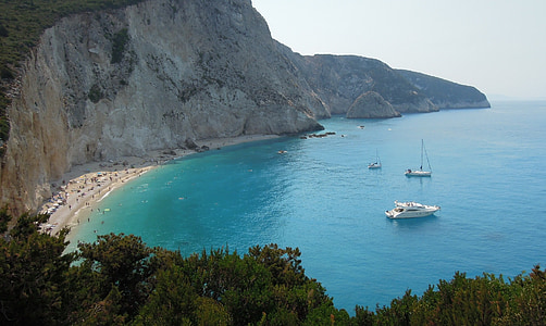white boat on body of water beside rock formation thumbnail