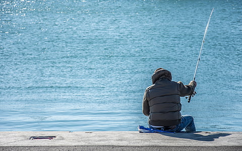 man sitting holding fishing rod thumbnail