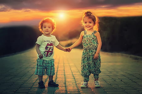 boy in white shirt and plaid shorts beside girl in overall pants thumbnail