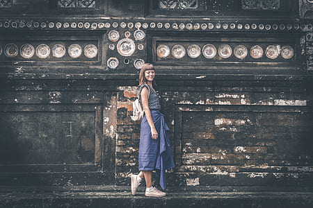 woman in blue dress standing in front of wall thumbnail