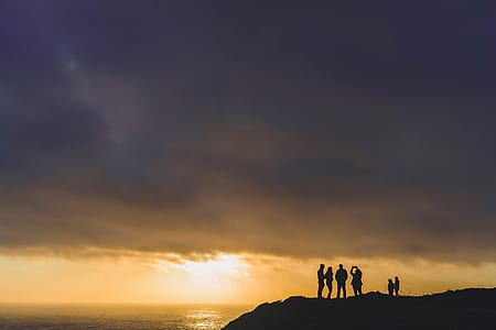 silhouette group of people standing near body of water thumbnail
