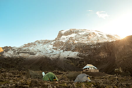 two grey and green tent pitched on rocky road near glacier mountain thumbnail