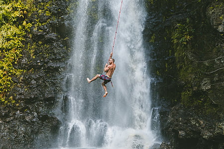 man holding a rope against the waterfall thumbnail