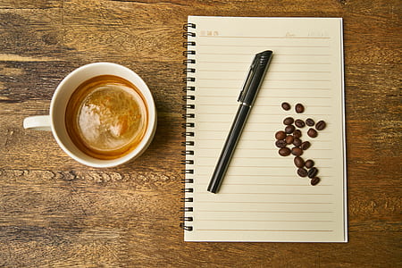 black ballpoint pen and coffee beans on white notebook thumbnail