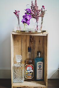three assorted bottles on rack with assorted petaled flowers on top thumbnail