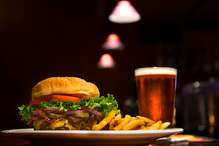 selective focus food photography of burger and fries on white ceramic plate with drinks thumbnail
