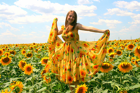 woman in yellow and orange sunflower-themed dress on sunflower field during daytime thumbnail