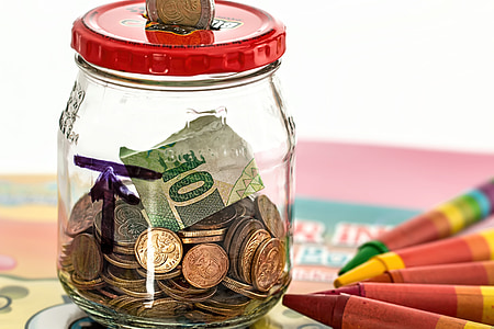 gold-colored coin in clear glass jar with 10 banknote near assorted-color crayons thumbnail