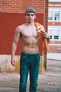 topless man wearing blue jeans standing on gray gravel thumbnail