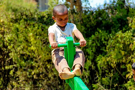 boy sitting on green seesaw thumbnail