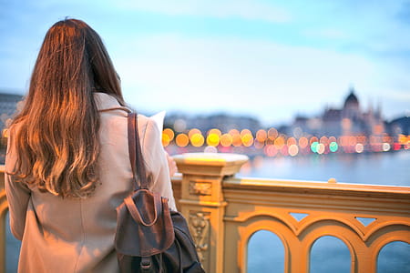 View From Behind, Young Woman In Trench Coat And Black Leather Backpack Looking Over Danube River thumbnail