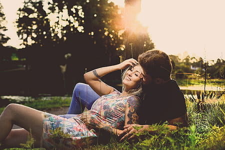woman in floral dress lying on man's chest during daytime thumbnail