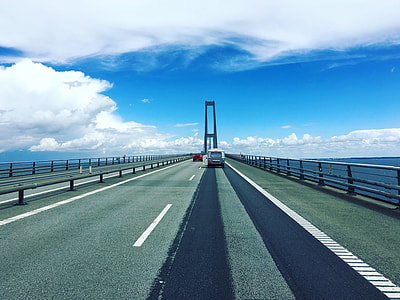 two vehicles on bridge under white clouds and blue sky at daytime thumbnail