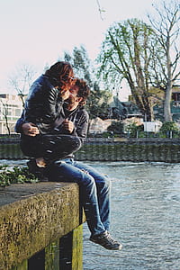 man hugging woman sitting on edge of concrete beam thumbnail