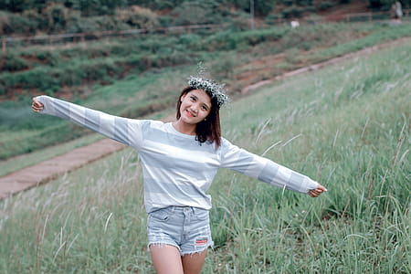 Selective Focus Photo of Woman Wearing Gray and White Striped Sweatshirt Standing on Green Grass Fields thumbnail