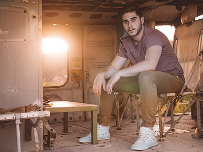 man wearing purple crew-neck shirt while sitting on brown chair thumbnail