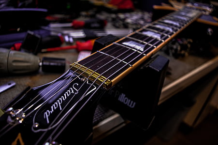 shallow focus photography of black electric guitar headstock thumbnail