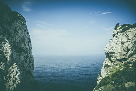 photography of gray cliffs near sea under blue sky thumbnail