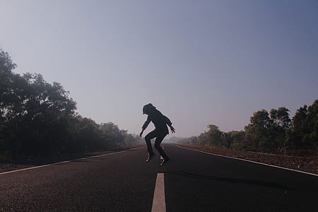 person doing jump on roadway at daytime thumbnail