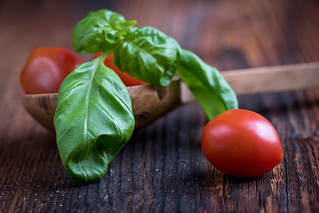 closeup photograph of red tomato on brown wooden surface near ladle with green leaf thumbnail