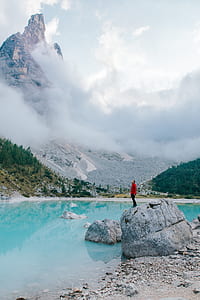 man standing on white boulder of rock by the lakeshore thumbnail