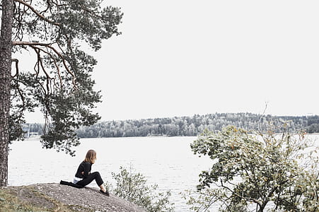 Woman Sitting on Gray Soil Near Body of Water thumbnail