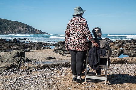 man and woman facing seashore during daytime thumbnail