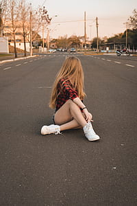 woman sitting on street road looking at parked vehicles thumbnail