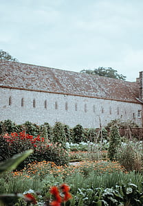 gray and brown house surrounded by grass and flowers thumbnail