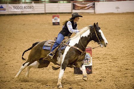 woman in black vest riding black and white horse thumbnail