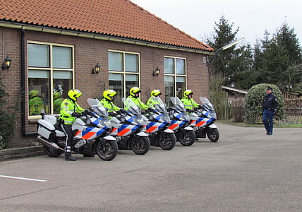 five police officers riding motorcycle in front of brown painted building thumbnail