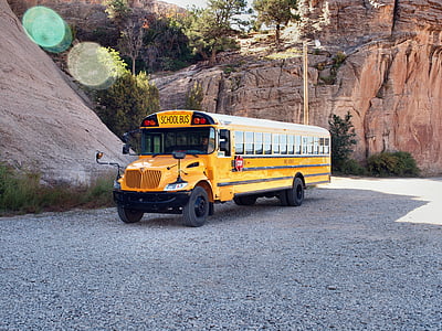 yellow bus near brown rock formation thumbnail